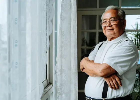 Confident ethnic man standing near window at home